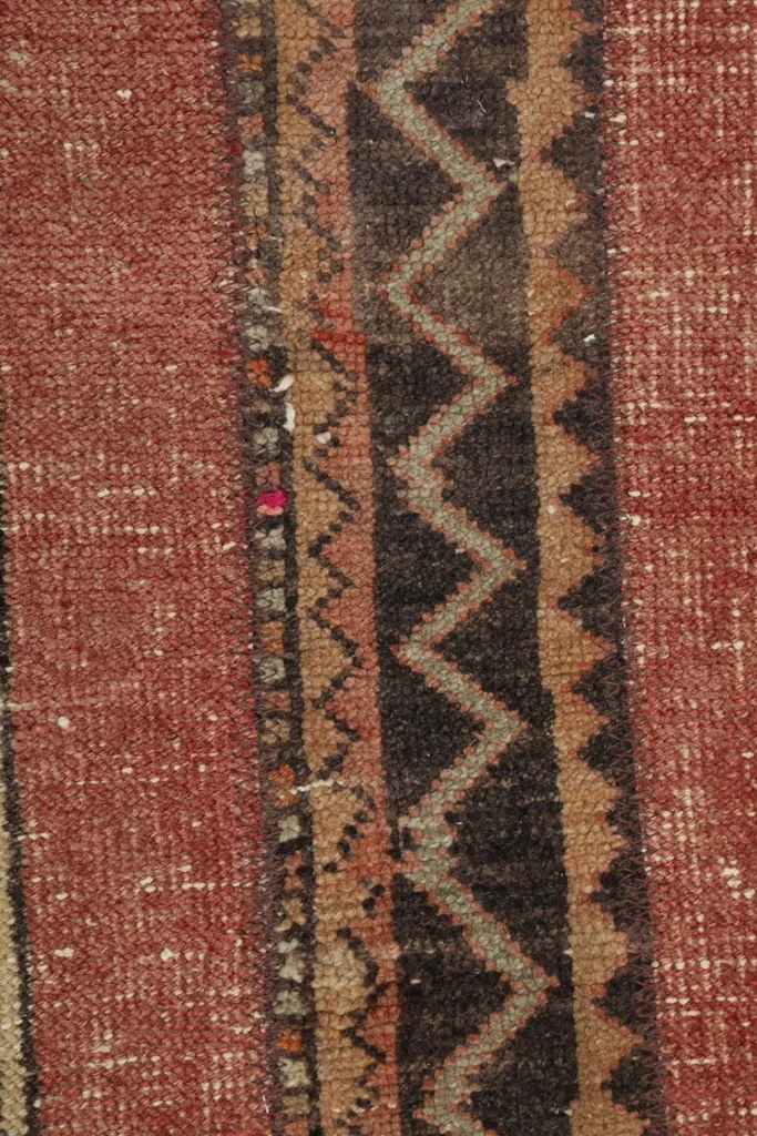 Detailed shot of the wool pile and the intricate weaving of the red and brown patterns.