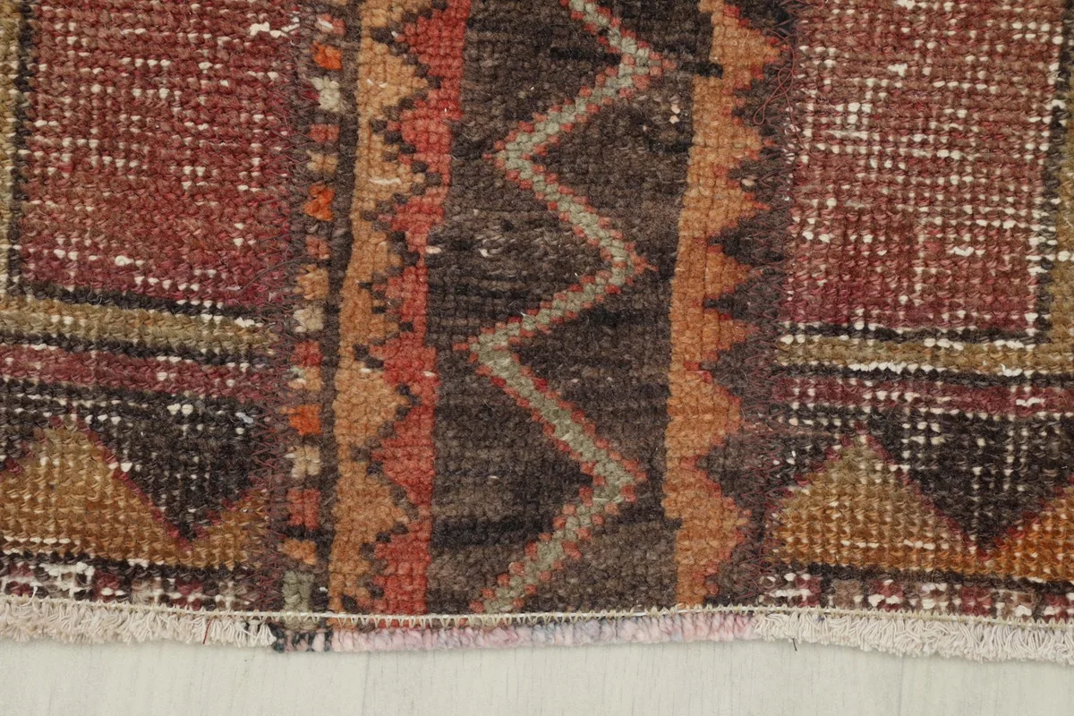 Close-up of the rug's edge, showing the tan border with brown triangular motifs and fringe.