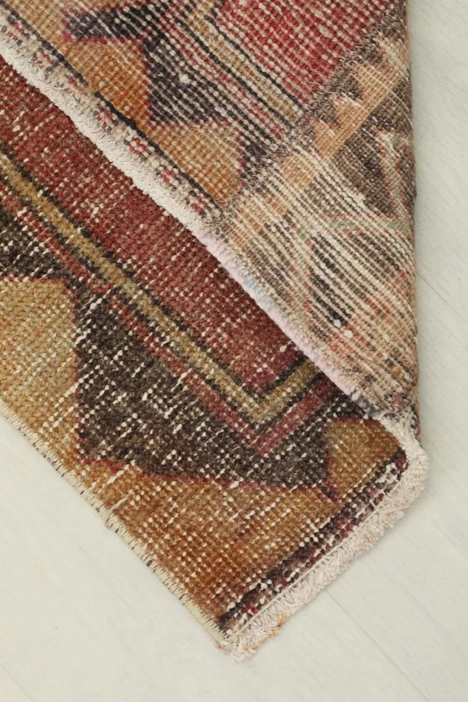 A corner of the rug folded back, displaying the reverse side and the hand-knotted cotton foundation.
