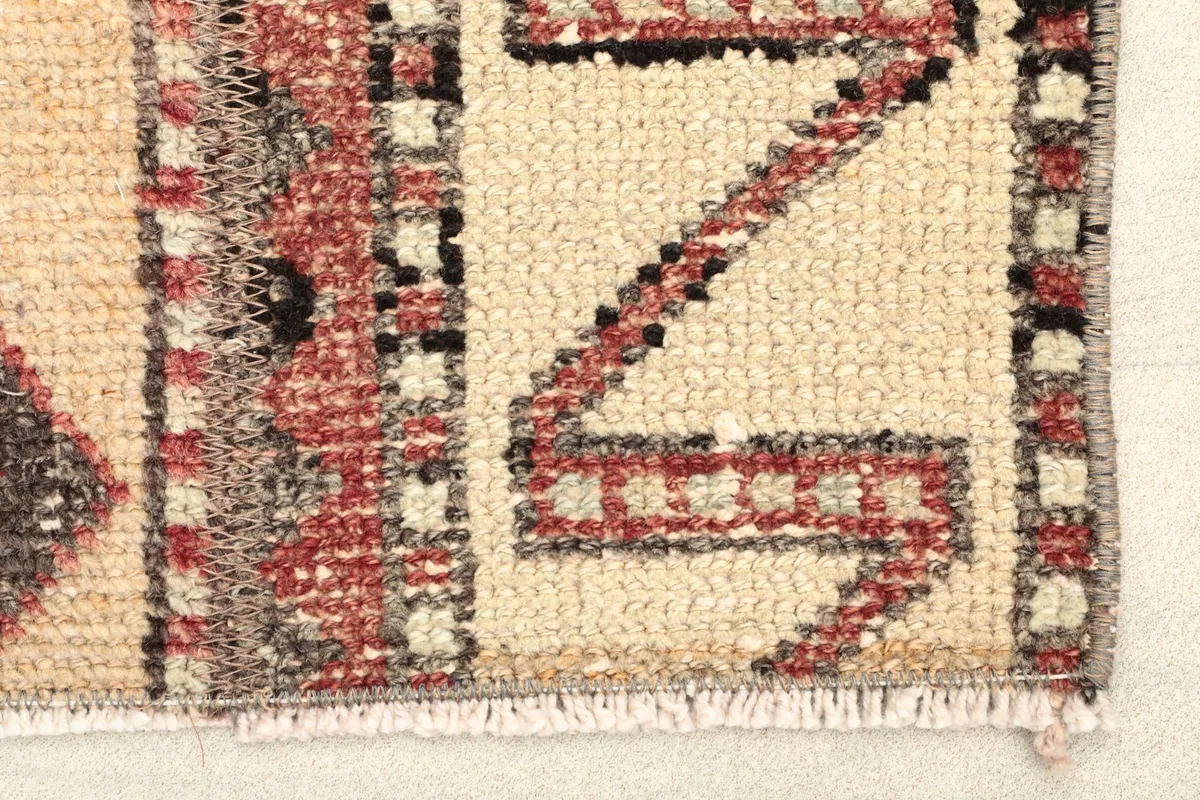 Close-up detail of the rug's edge, showing the hand-knotted texture and a zigzag pattern in tan and rust.