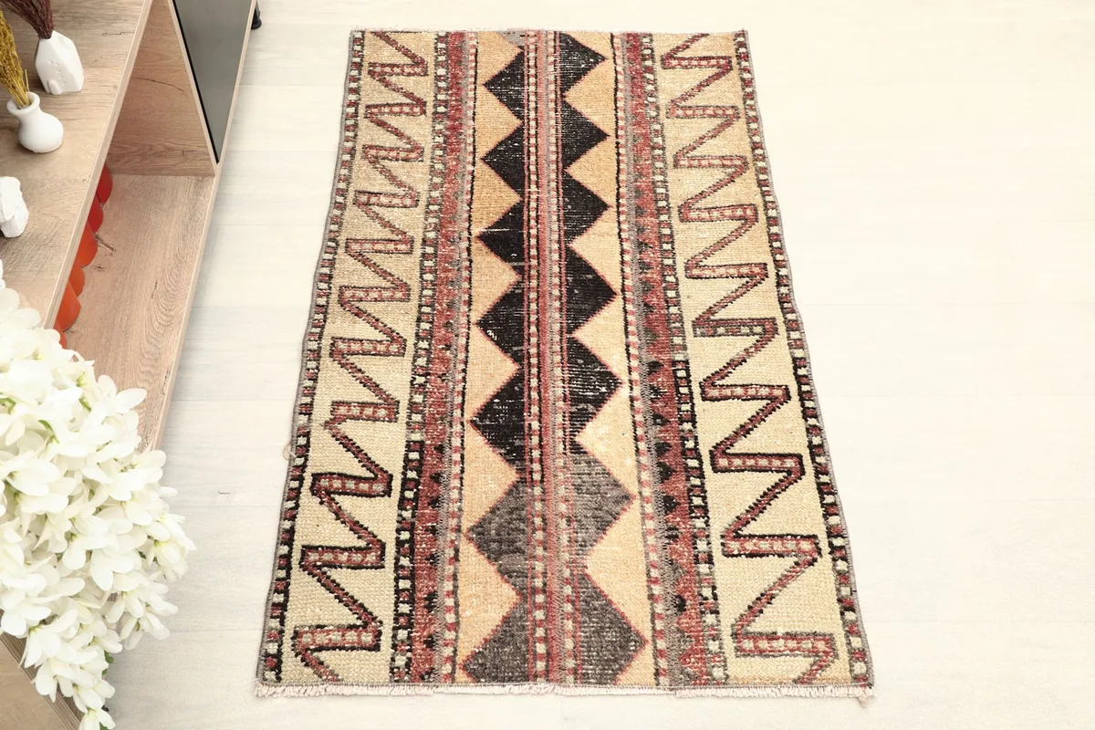 Overhead view of the vintage rug, showcasing its full pattern of zigzags and diamonds on a tan field.