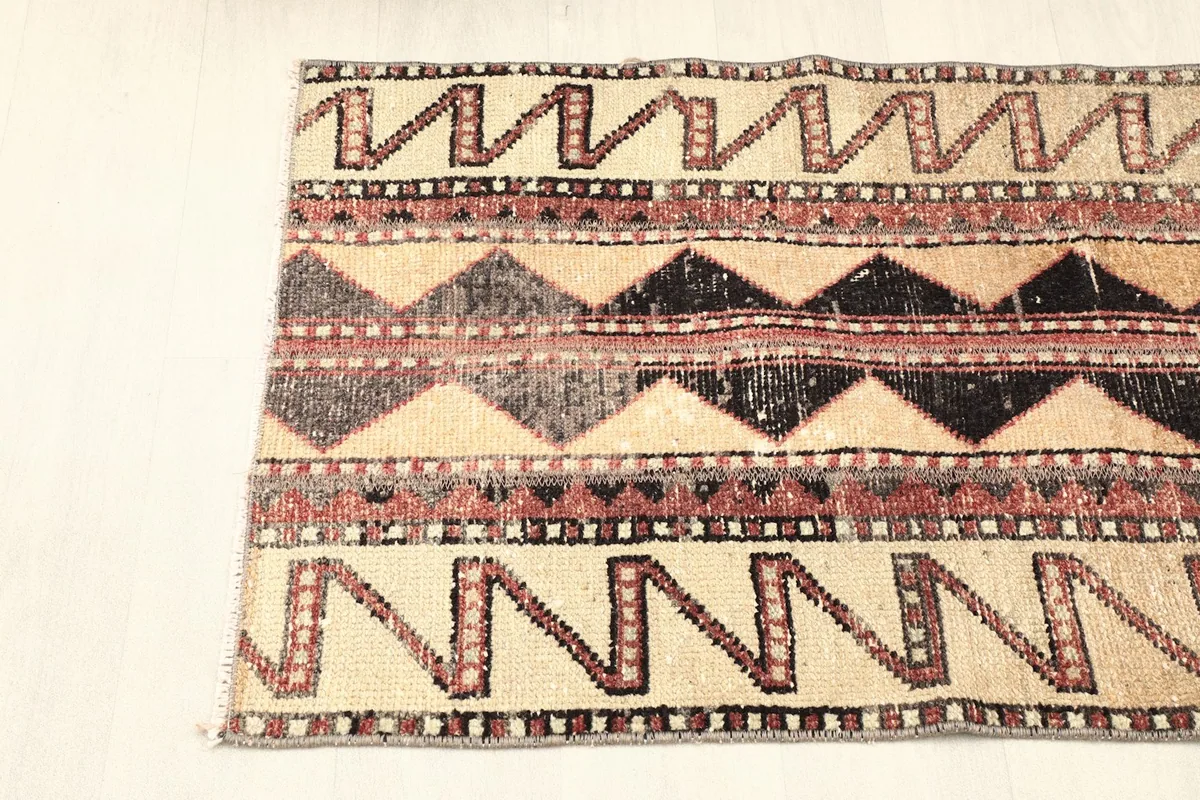 Partial overhead view of the rug, focusing on the vibrant geometric bands and fringe detail.