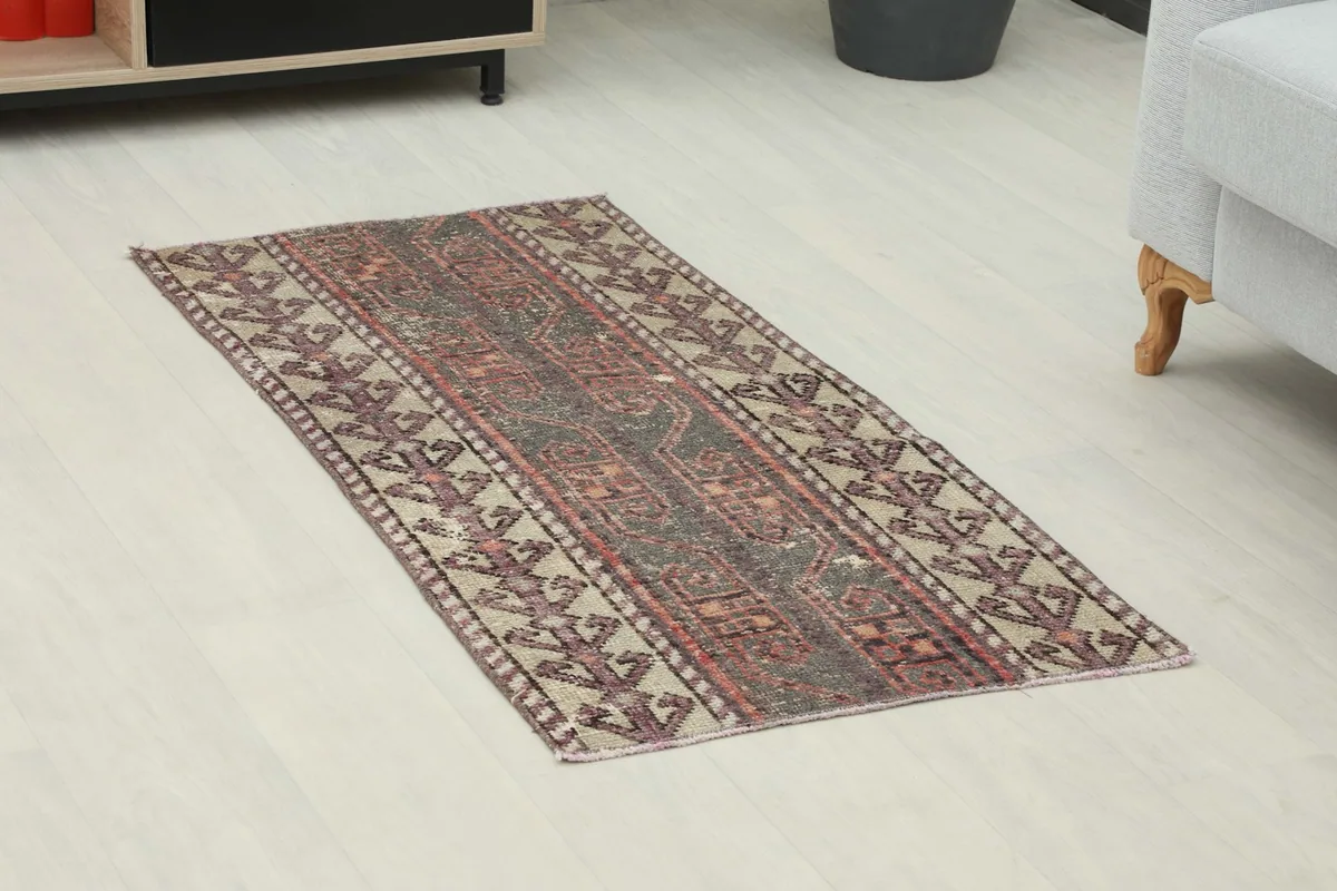 Angled view of the charcoal and beige vintage rug, highlighting its placement in a room setting.