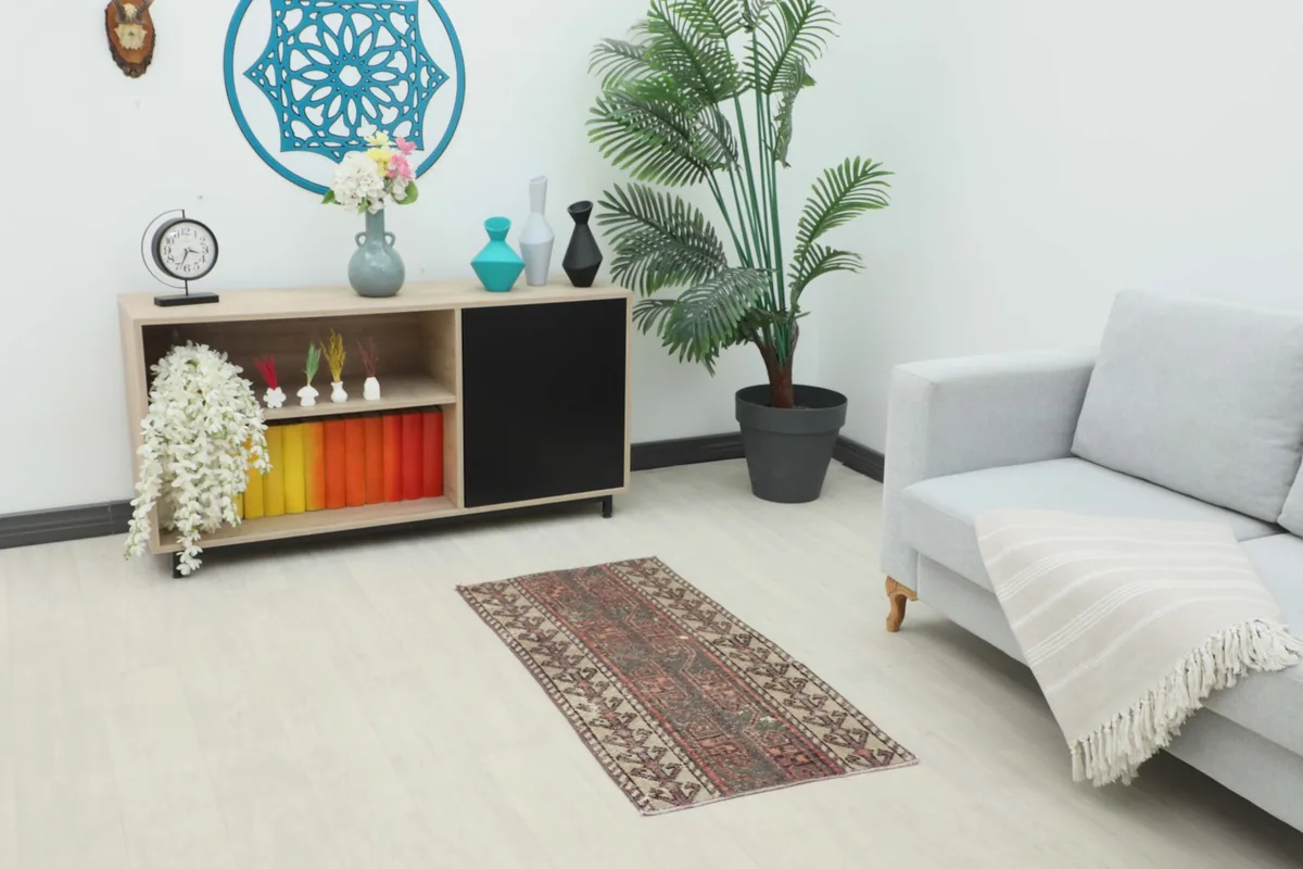 Vintage Anatolian rug displayed in a modern living space with a sofa and cabinet, showing its scale.