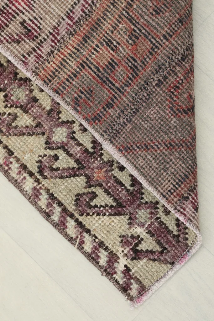 View of the rug's underside, revealing the hand-knotted cotton foundation and the reverse of the pattern.
