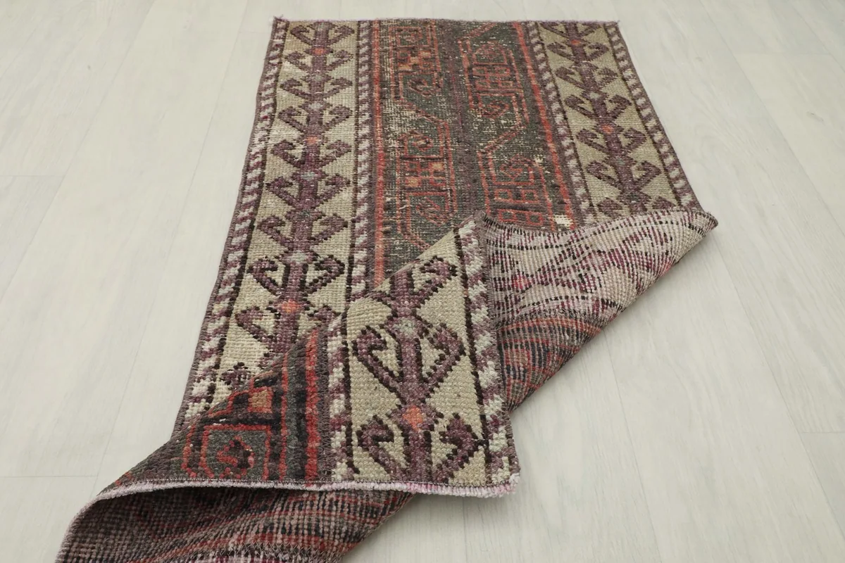 The vintage rug partially folded, showing both the front and back textures and colors.