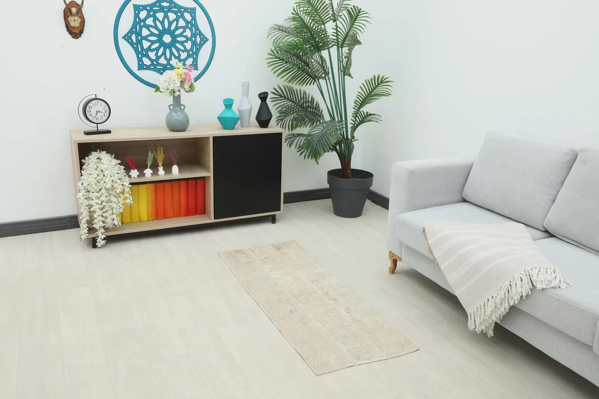Vintage tan runner rug placed in a living space with a couch and console table, showing its scale.