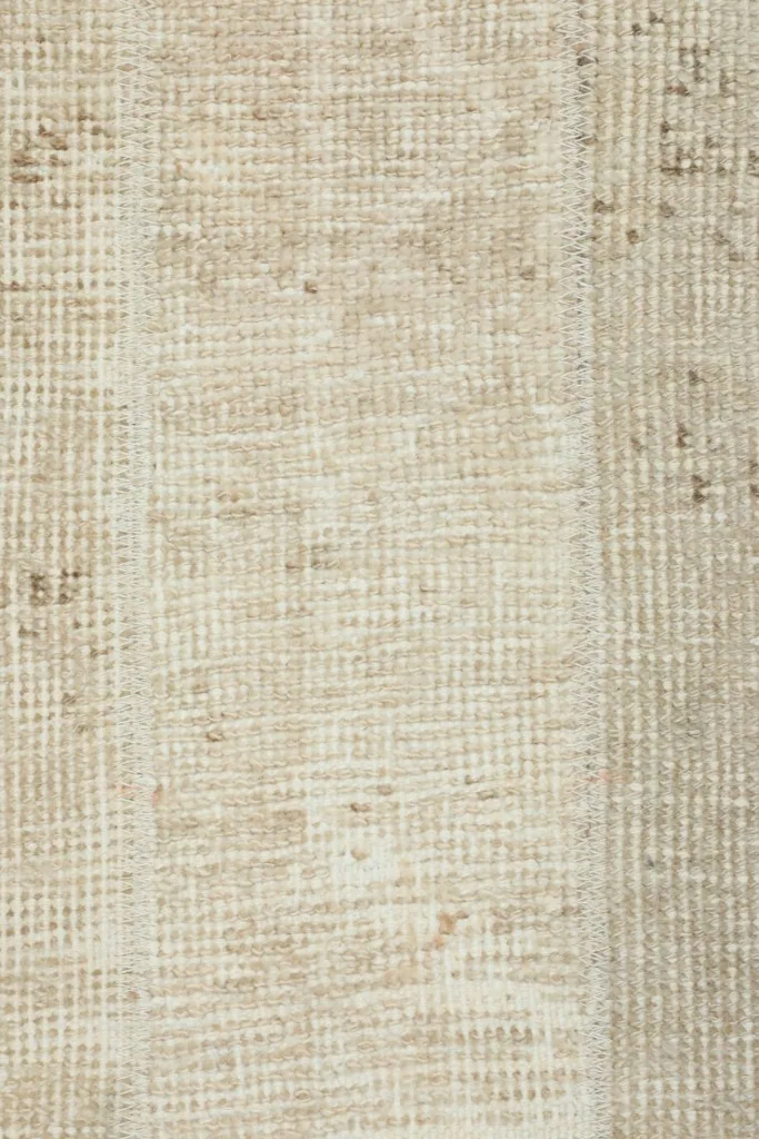Detailed overhead view of the rug's fibers and subtle color shifts in the tan and beige tones.