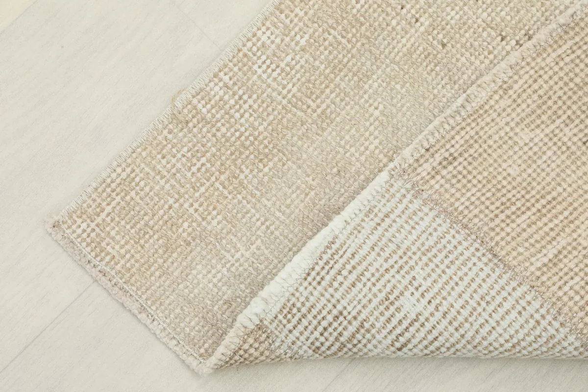 Corner of the rug folded to show the cotton foundation and the reverse side of the hand-knotting.