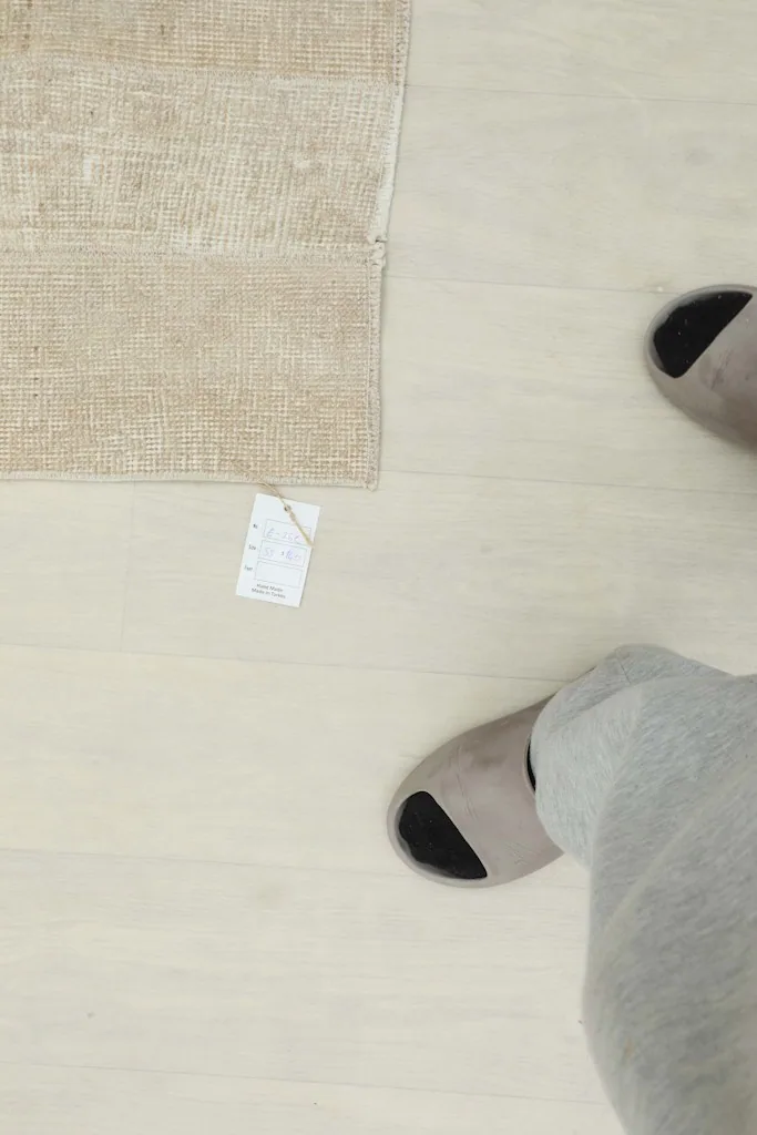 Overhead view of feet in slippers next to the rug, providing a sense of scale and everyday use.