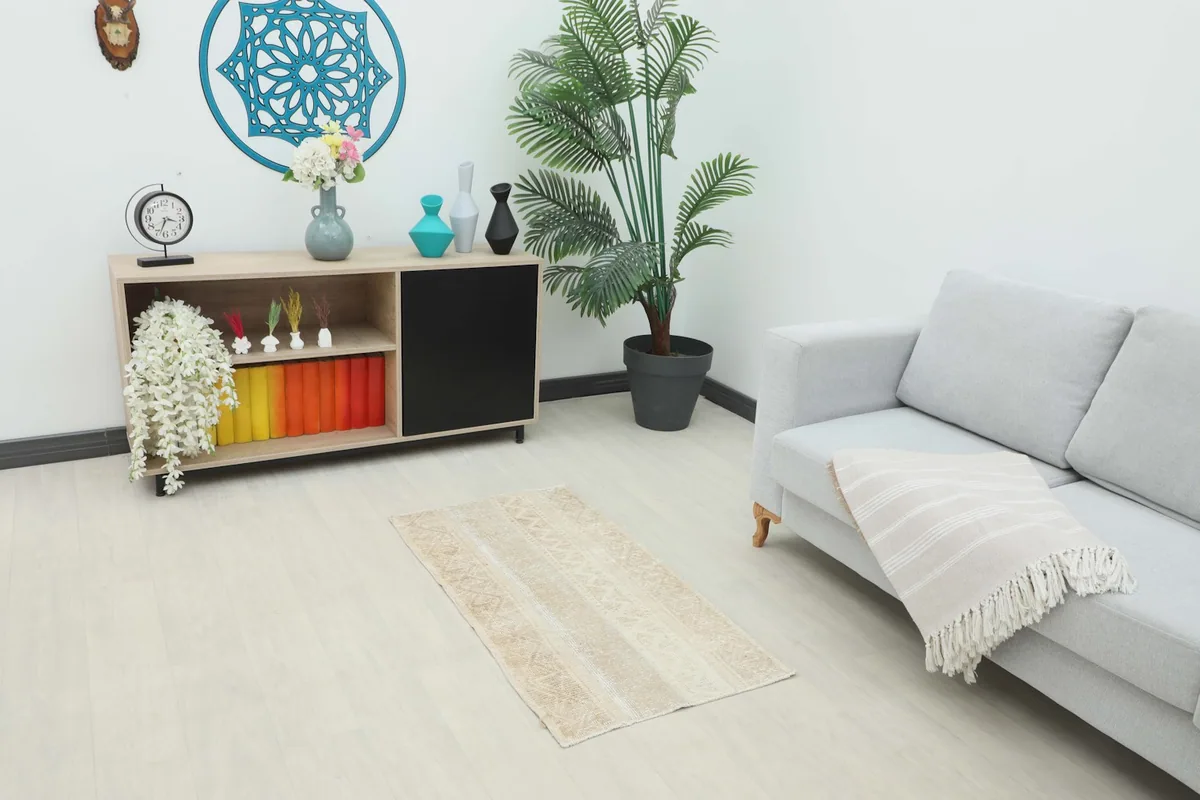 Vintage beige and cream rug placed in a living room setting next to a sofa and cabinet