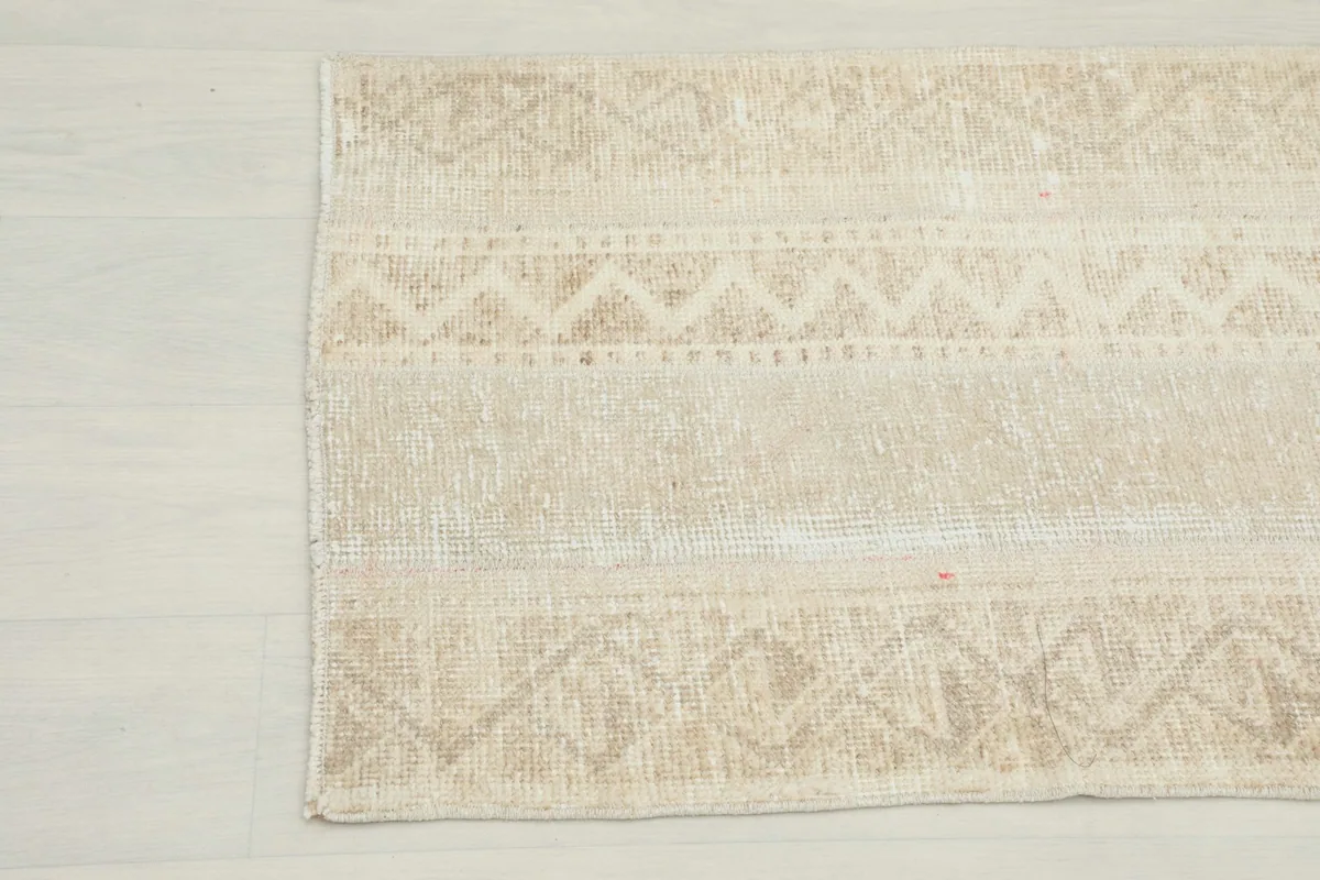 Detailed view of the vintage rug's tribal patterns and color variations near the edge