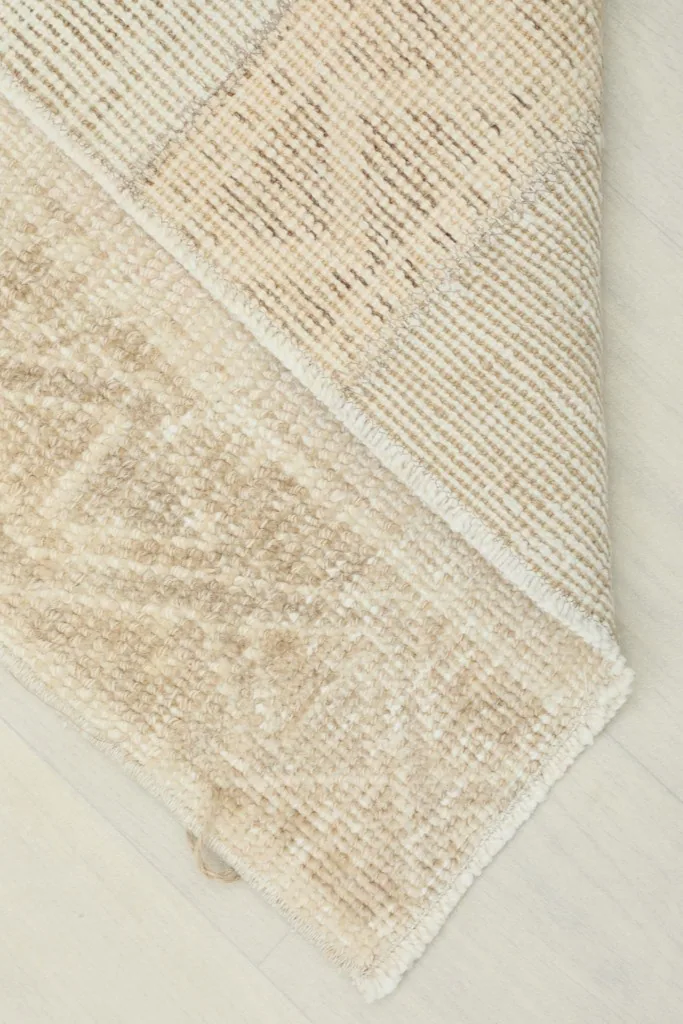 View of the rug's backside, revealing the cotton foundation and knotting