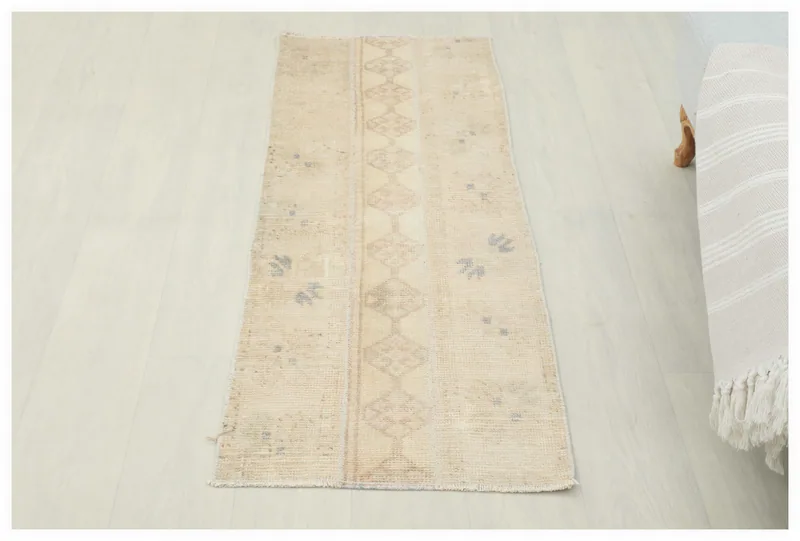 Full top view of the 1'9" x 4'6" beige vintage Anatolian runner on a white floor.