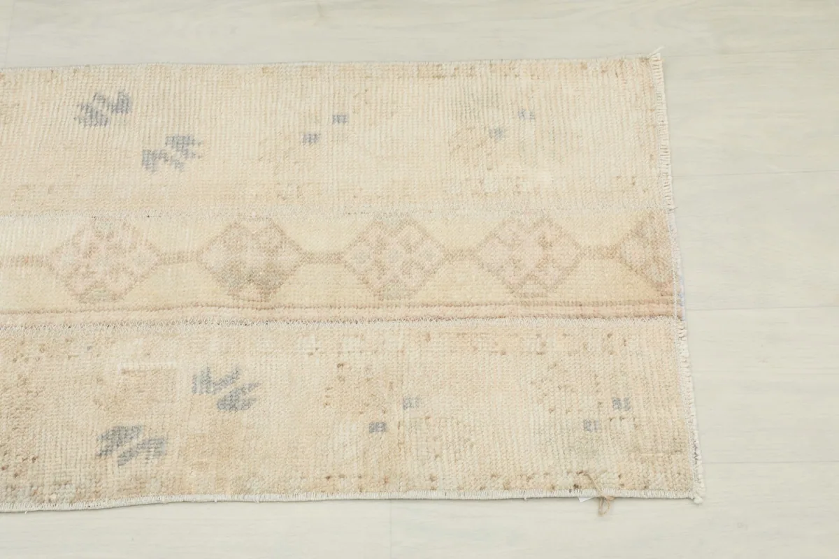 Close-up detail of the rug's end, showing the faded gray and tan geometric motifs.