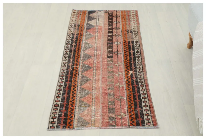 Full top view of the 2x5 vintage Anatolian rug with rose, orange, and black geometric patterns
