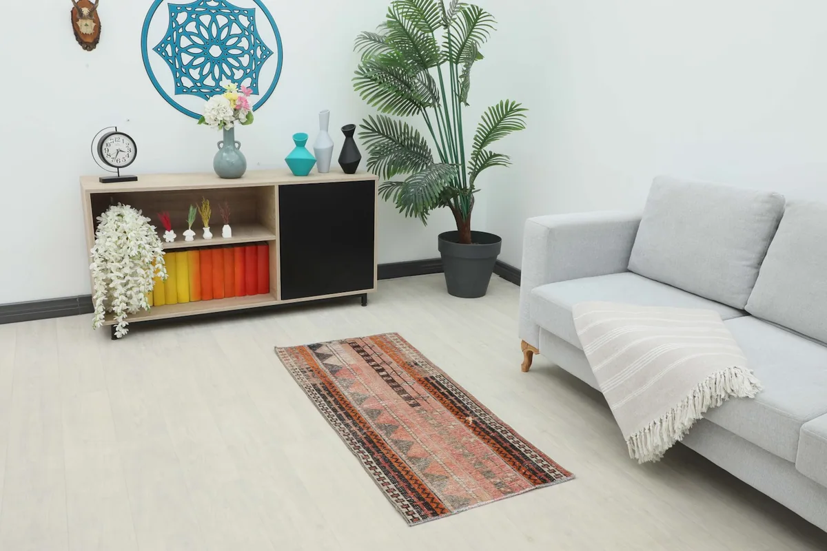 Vintage Anatolian rug placed in a living room setting next to a sofa and cabinet