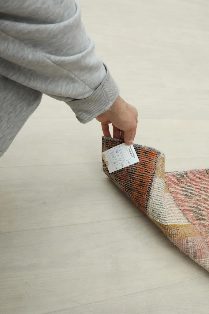 A hand touching the rug's pile, demonstrating its low profile and soft texture