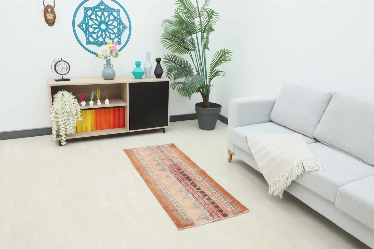 Vintage Anatolian runner rug placed in a living room setting with a sofa and cabinet.