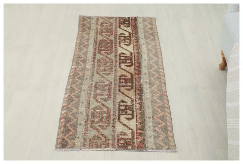 Full top view of the 1'10" x 4'0" beige and gray tribal area rug on a white background