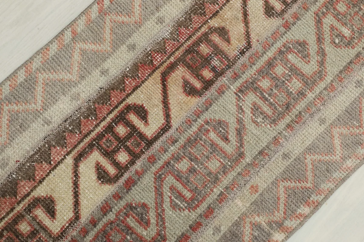 Diagonal close-up of the rug's patterns, including rust and brown tribal elements on beige and gray fields
