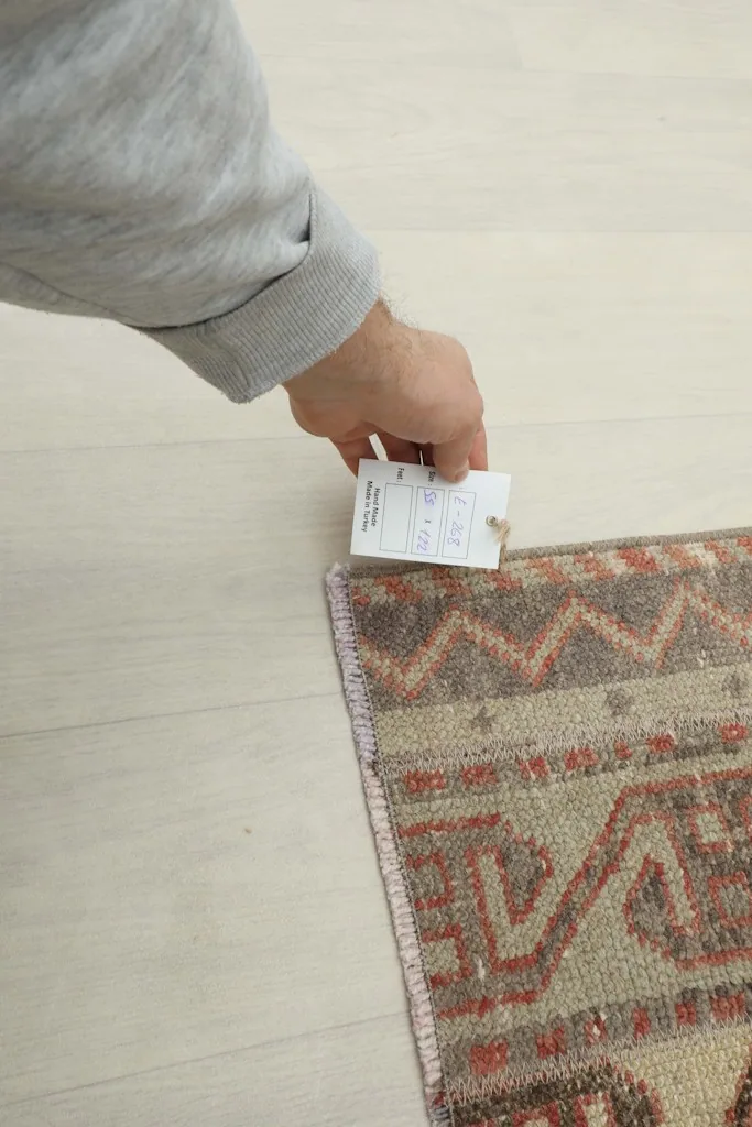 Hand holding a size tag next to the rug, showing its texture and weave