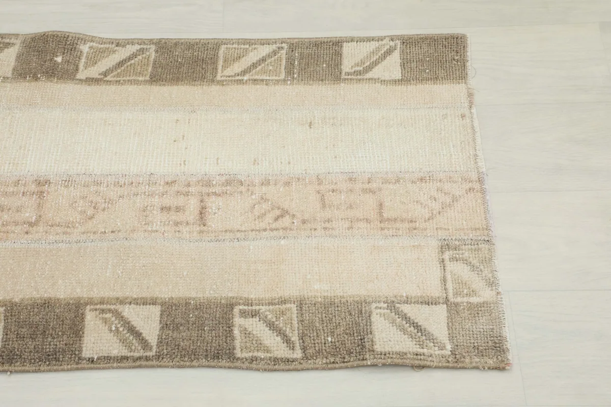 Close-up of the rug's end, showing the striped pattern and subtle geometric details.