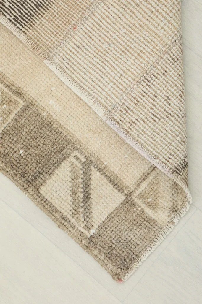 Corner of the rug folded back to reveal the hand-knotted cotton foundation.