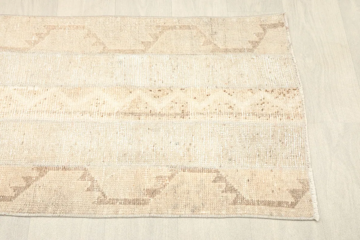 Angled view of the rug's bottom half, displaying the gentle patina and geometric border elements.