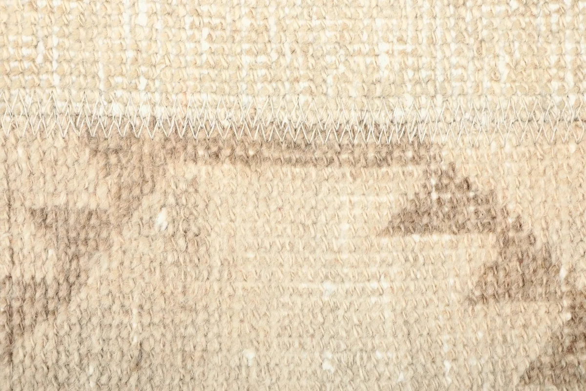Close-up of the beige and tan wool pile, showing the natural variations and pattern details.