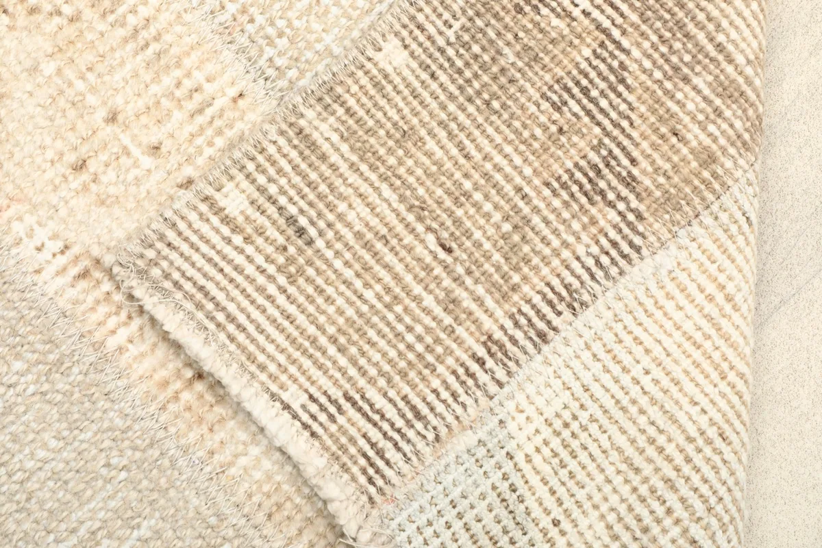 View of the rug's folded corner, revealing the cotton foundation and hand-knotted construction.
