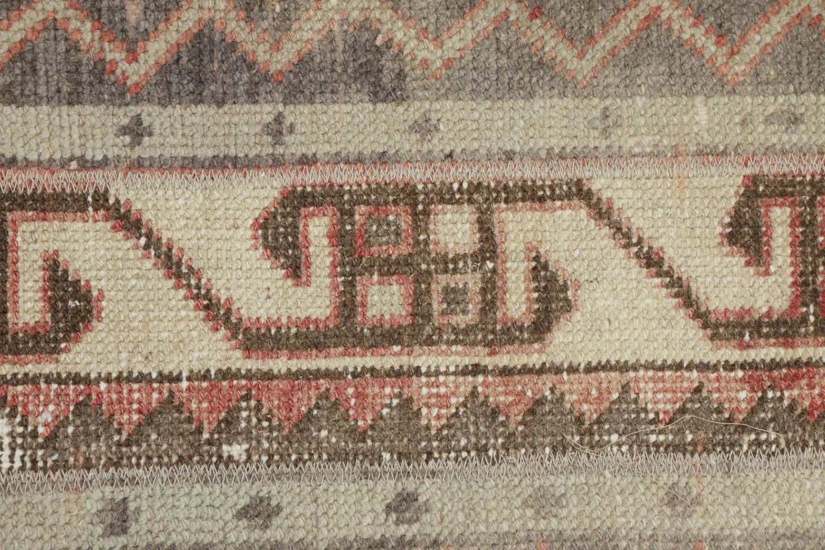 Detailed view of the beige, brown, and rose tribal motifs and chevron patterns within the stripes.