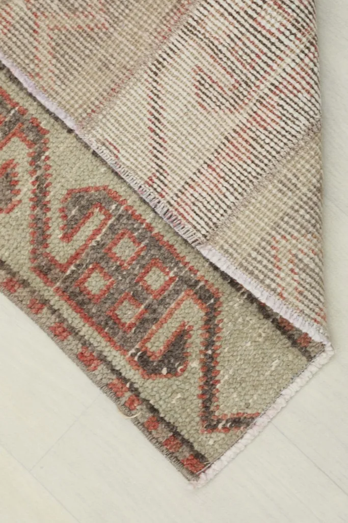 View of the rug's backside and corner, revealing the hand-knotted cotton foundation.