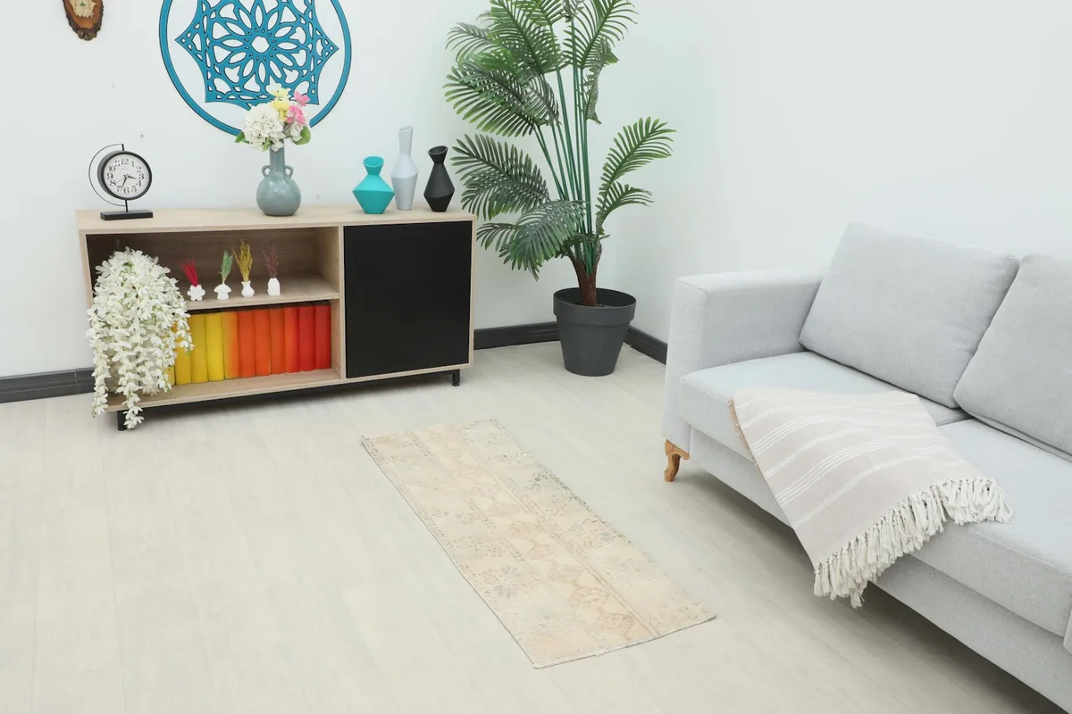 Cream runner placed in a modern living room setting next to a gray sofa and wooden console.