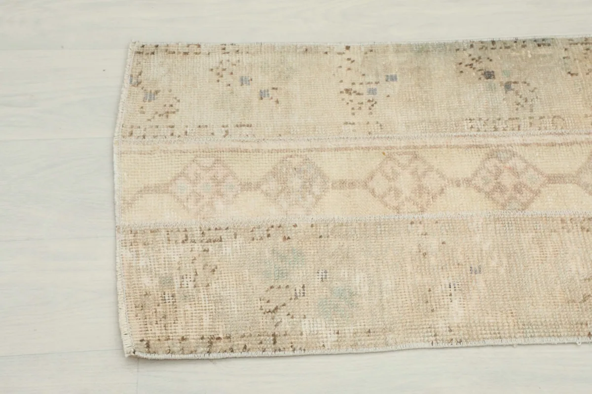 Close-up showing the faded motifs and texture of the vintage cream Anatolian runner.