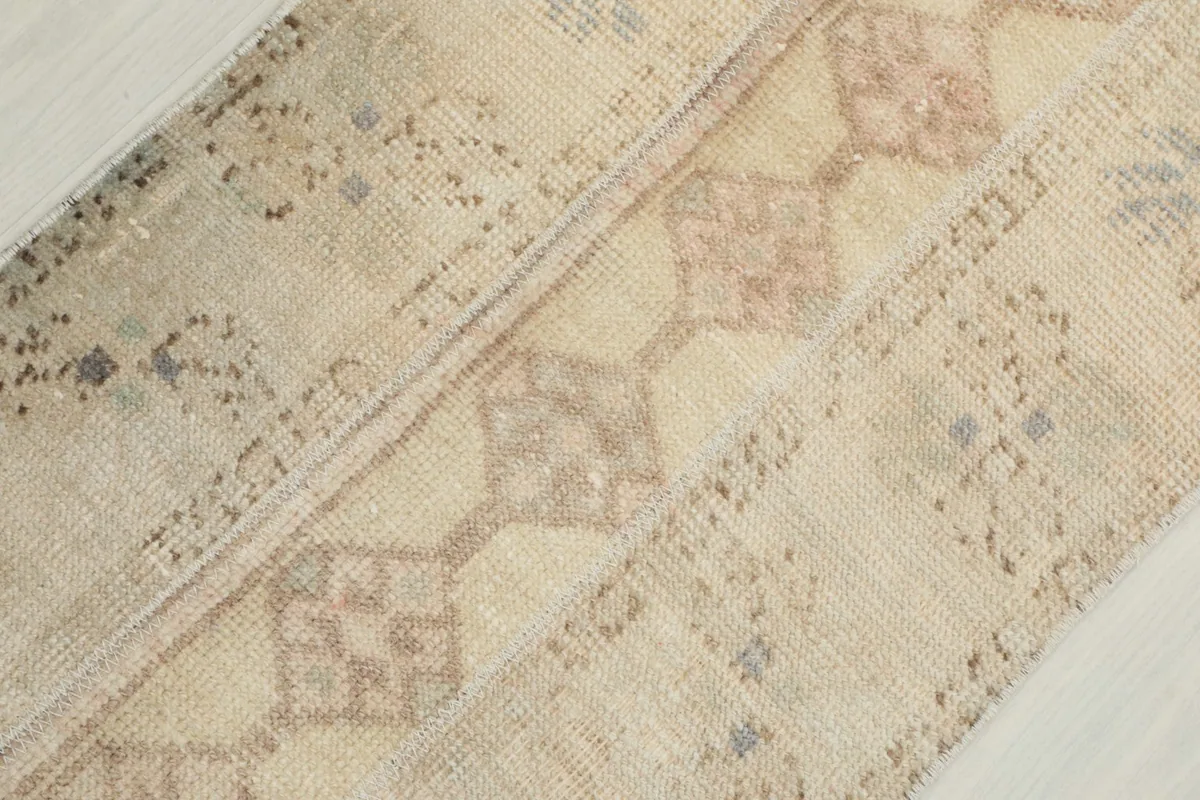 Diagonal close-up of the hand-knotted wool pile and geometric design on the cream runner.