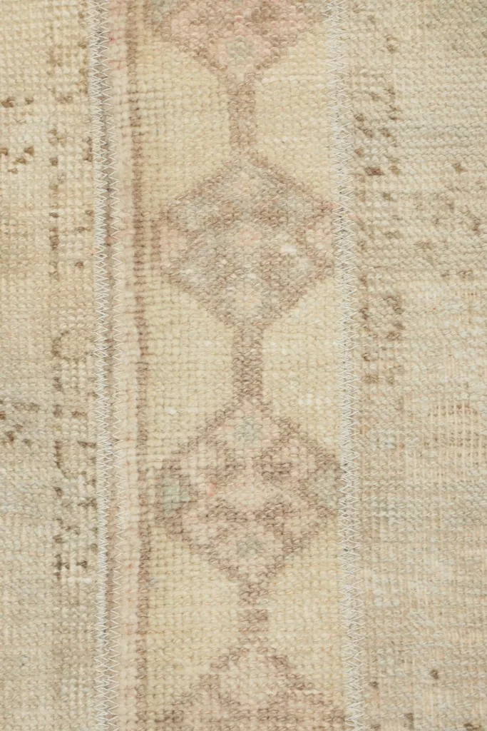 Detailed view of the central diamond-shaped motifs in beige and tan on the cream field.