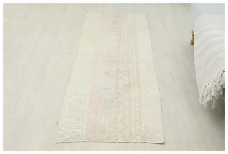 Full overhead view of the beige and rose vintage Anatolian runner rug on a light floor.
