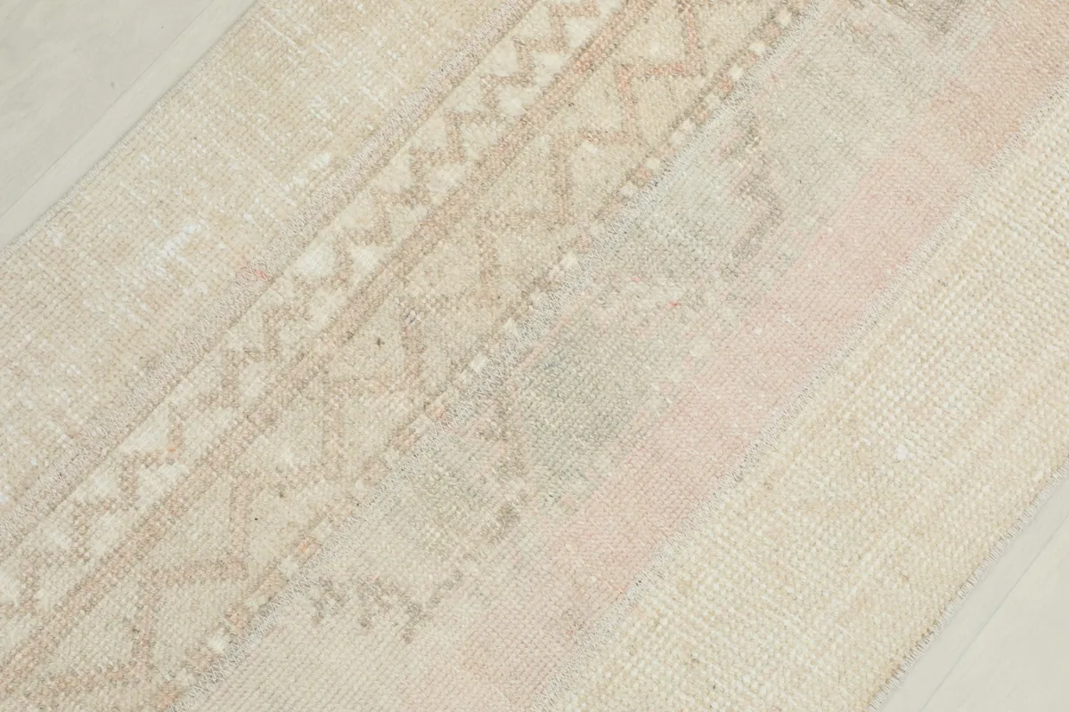 Angled close-up of the rug's patterns, emphasizing the tribal geometric motifs in beige and rose.