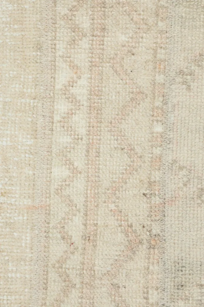 Extreme close-up of the rug's low wool pile and the subtle variations in color and pattern.