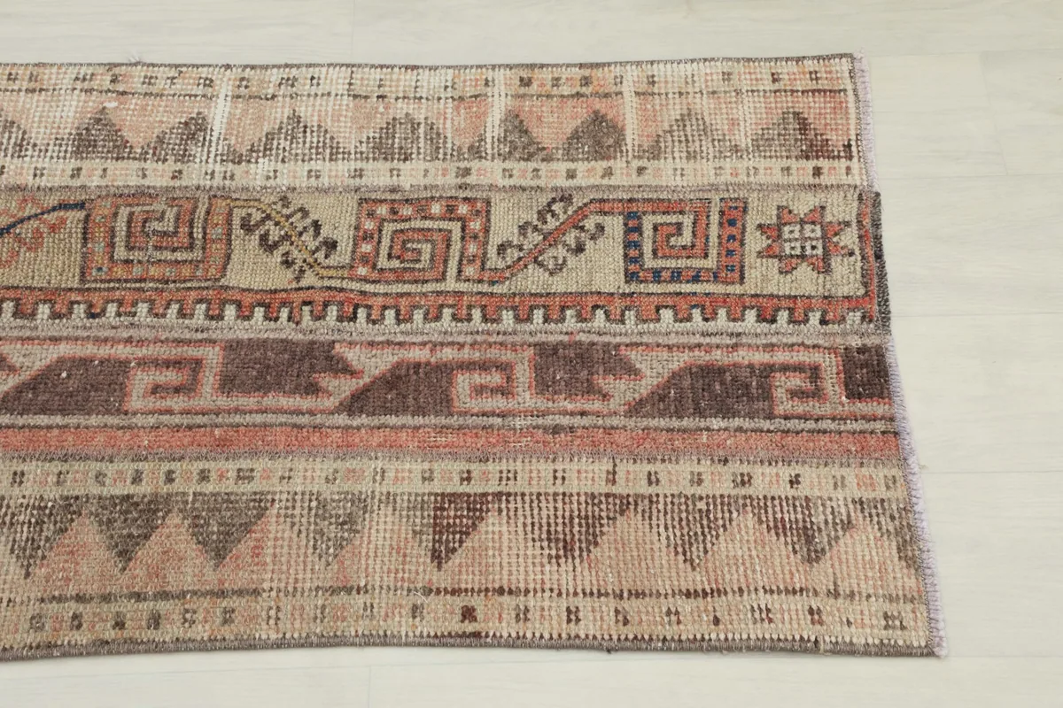 Close-up detail of the vintage rug's tribal geometric patterns and beige, rust, brown colors.