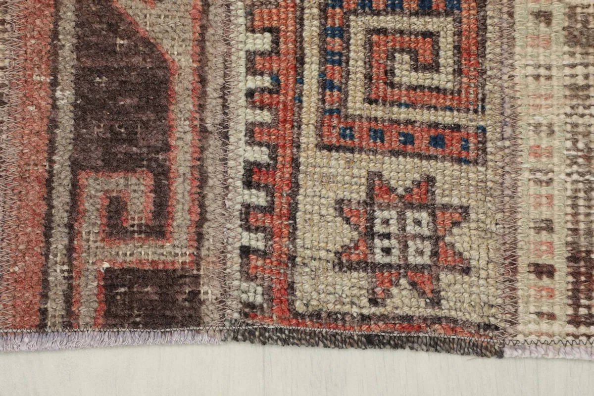 Extreme close-up of the rug's tribal star motif and geometric borders in rust and beige.