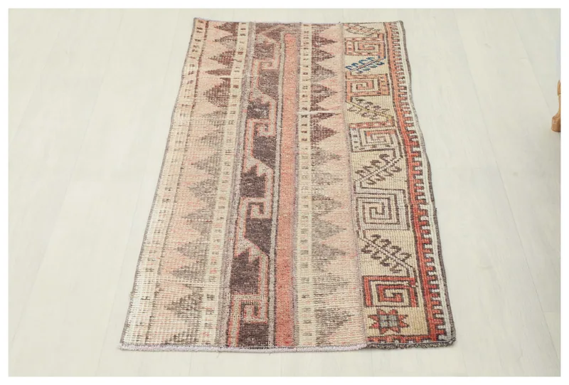Full top view of the 2x4 beige, rust, and brown striped tribal vintage Anatolian rug on a white floor.