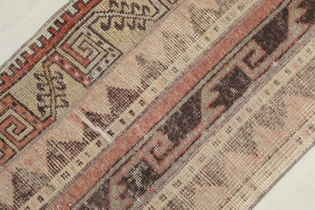 Diagonal close-up of the rug's surface, emphasizing the different striped panels and their motifs.