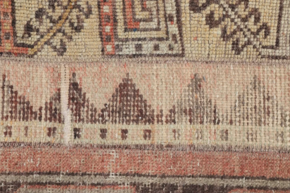 Detailed view of the low pile and intricate knotting, showcasing the rug's vintage texture and color variations.