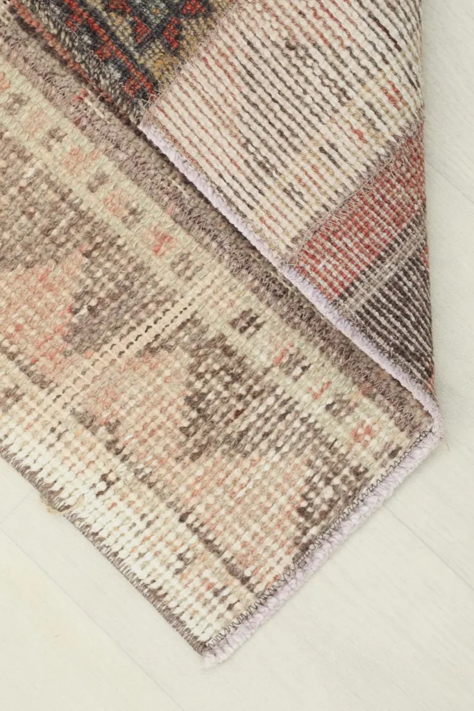 Folded corner of the rug, showing the wool pile and cotton foundation from the side.