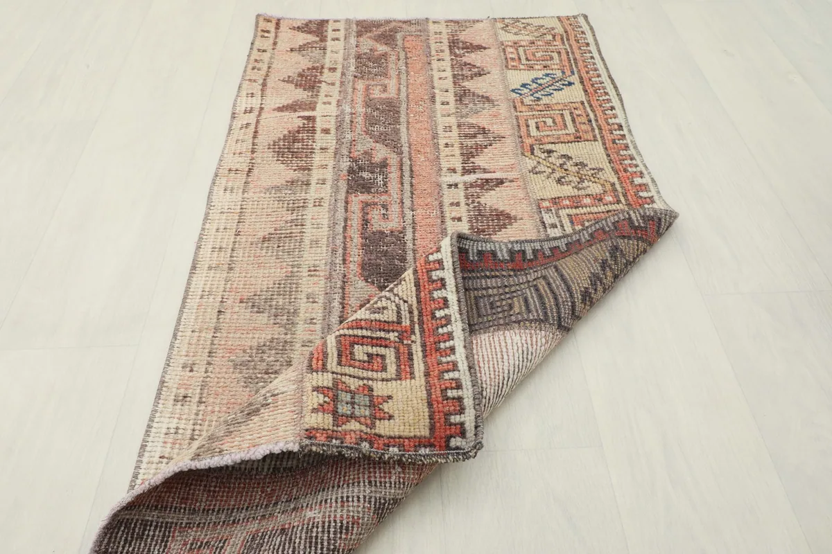Rug partially folded, illustrating its flexibility and the reverse side of the hand-knotted construction.