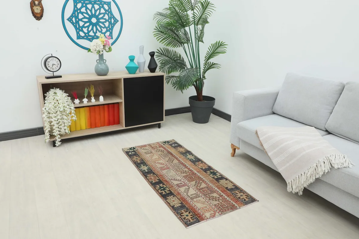 Vintage Anatolian rug displayed in a room setting, next to a sofa and cabinet