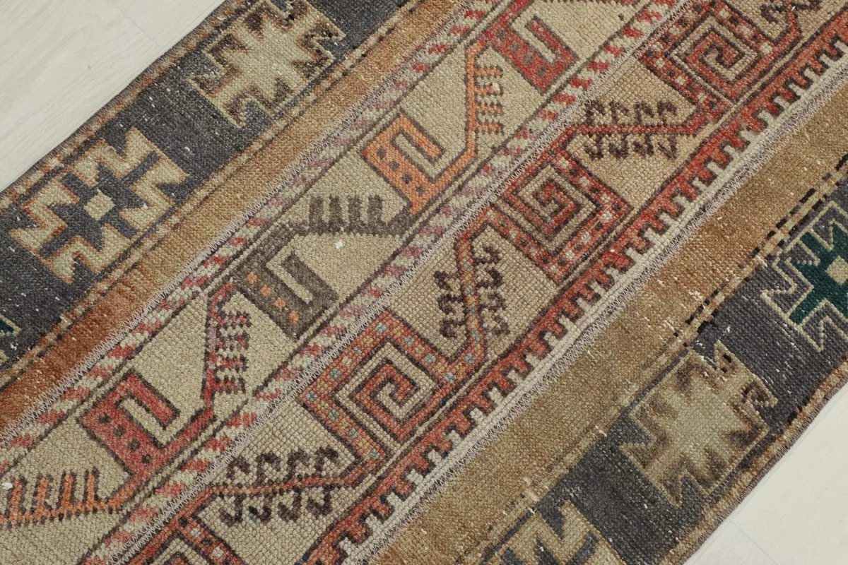 Close-up of the rug's texture and a section of its beige, rust, and gray design