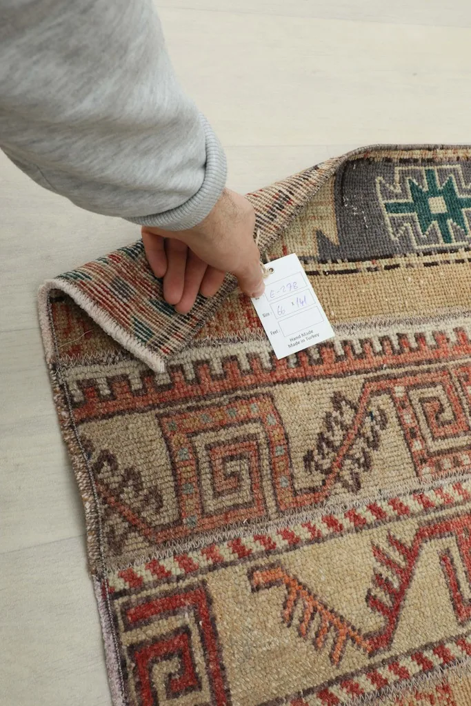 Hand holding the corner of the rug, revealing the back of the hand-knotted weave